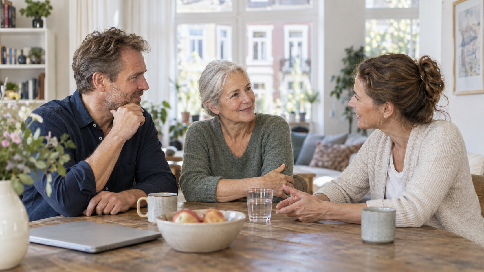 Drei Erwachsene sprechen am Tisch über ein geerbtes Haus